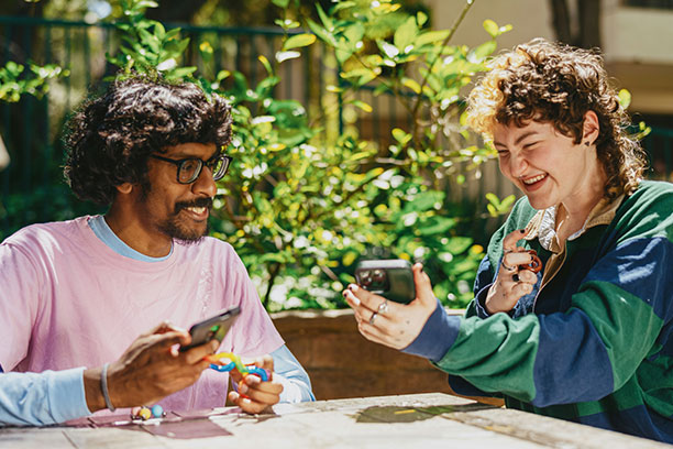Two people at a table, smiling and chatting outdoors